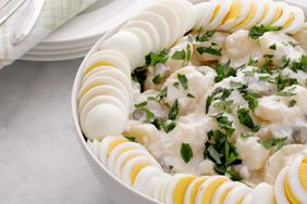 Potato salad garnished with parsley and sliced boiled eggs in a white bowl