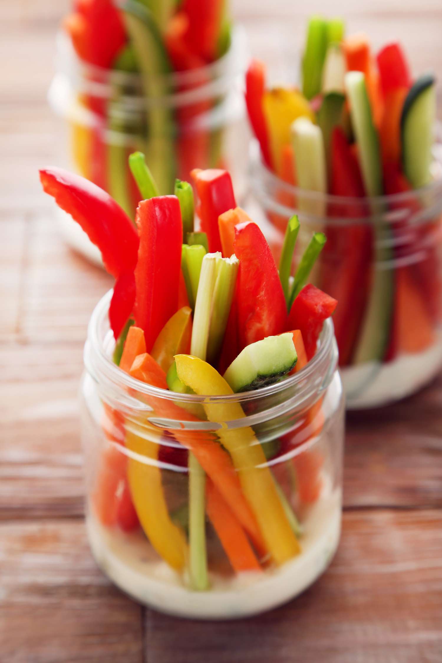 Sliced vegetables in jars on brown wooden table