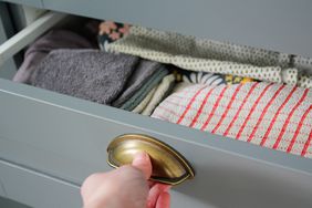 close up of a woman pulling a grey dresser drawer open