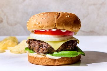 Hamburger with lettuce tomato onion cheese and a sesame seed bun