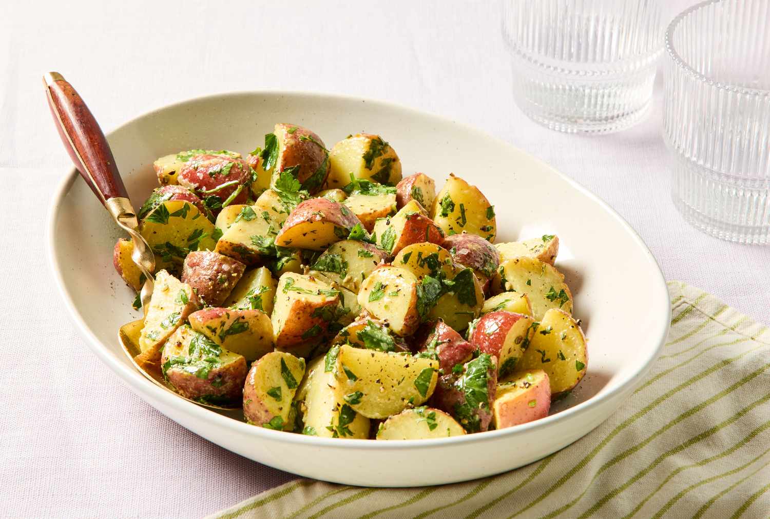 Bowl of a potato salad with herbs, placed on a striped napkin