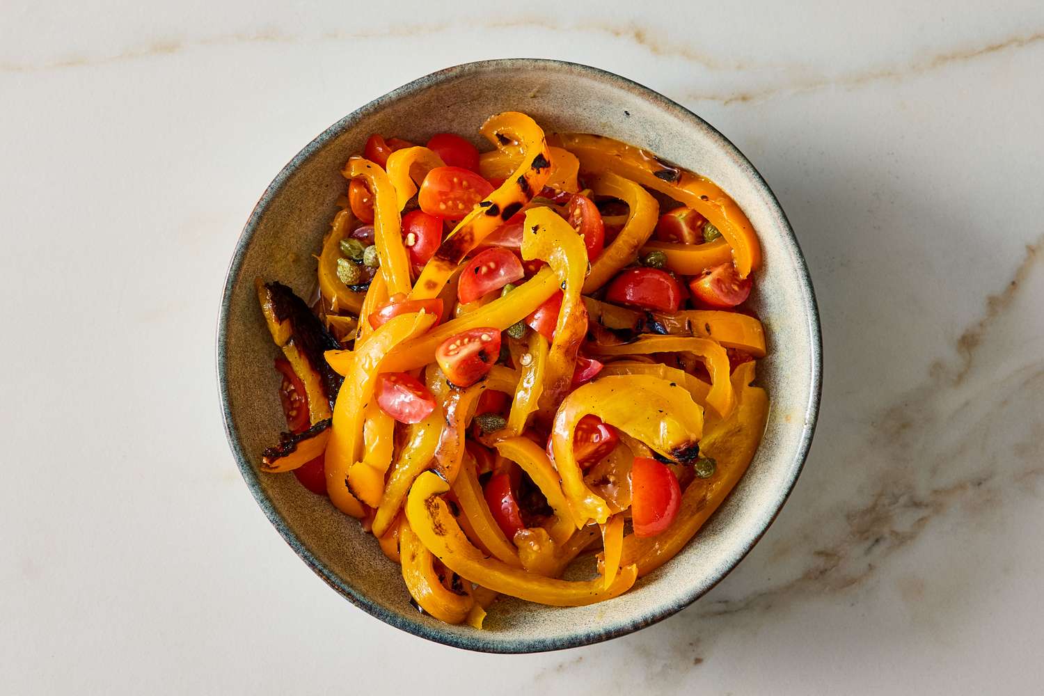 A bowl of grilled pepper bruschetta showcasing slices of roasted peppers and cherry tomatoes with seasonings