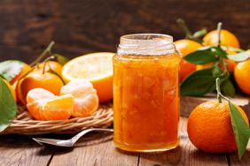 Jar of marmalade surrounded by oranges and a spoon