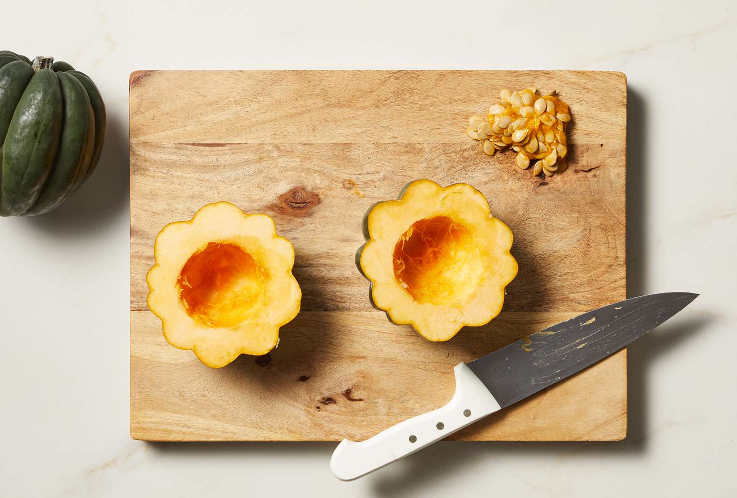 overhead view of acorn squash being cut on board