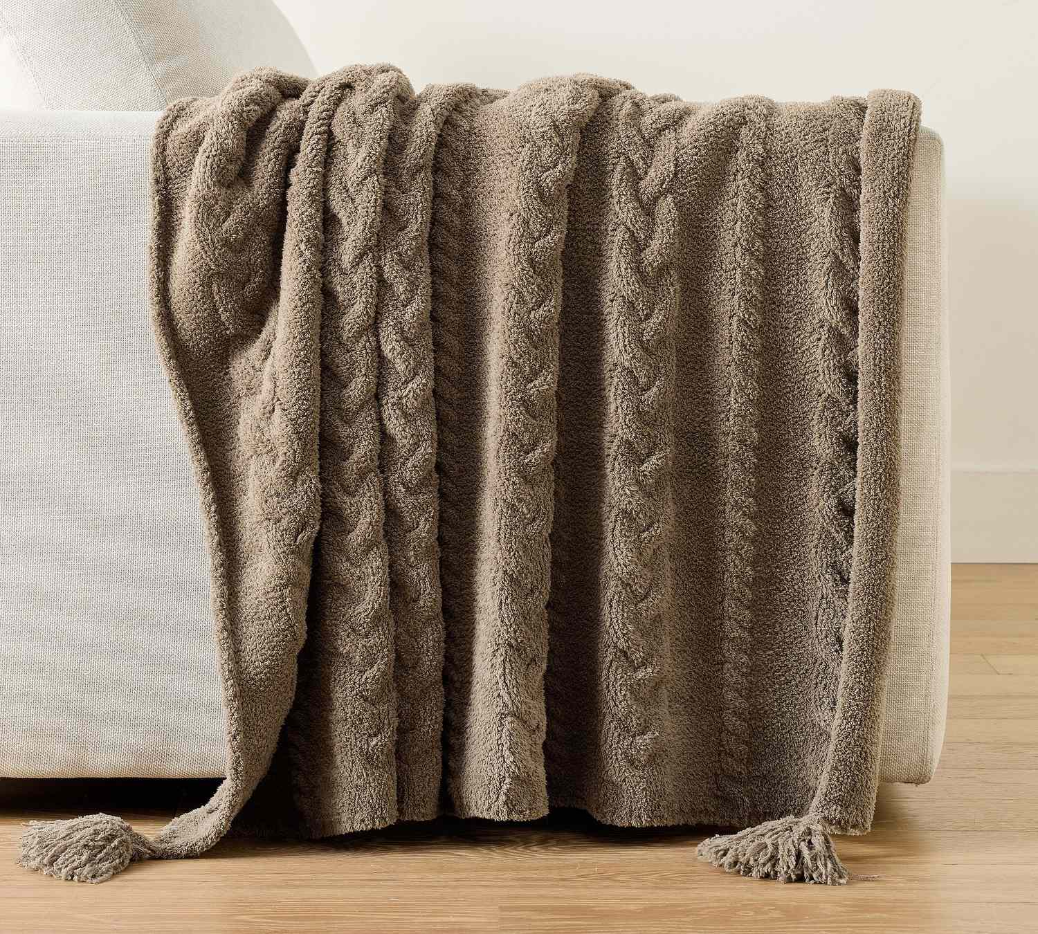 A textured throw blanket draped over the arm of a sofa