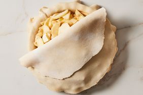 sliced apples in a pie crust with partially covered top layer of pie crust