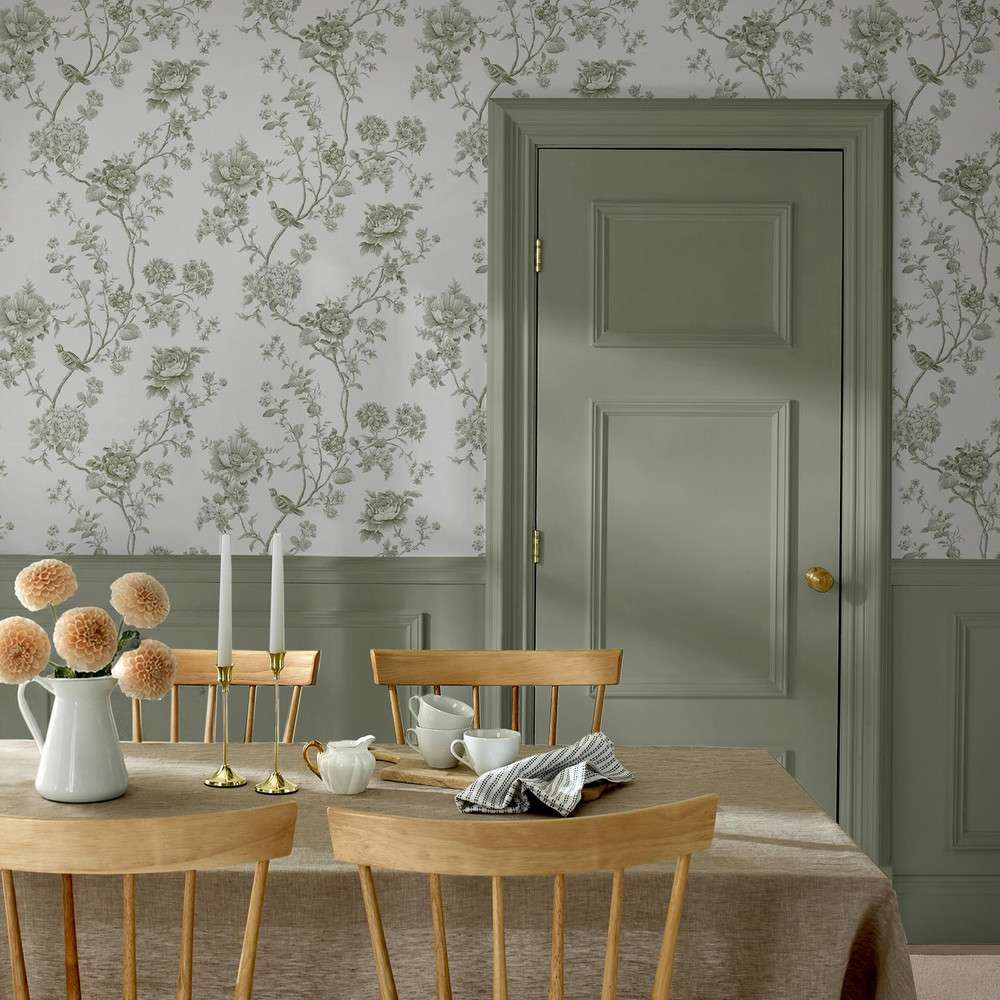 Dining room interior with floral wallpaper wooden chairs and table with a neutral tablecloth and decorative items