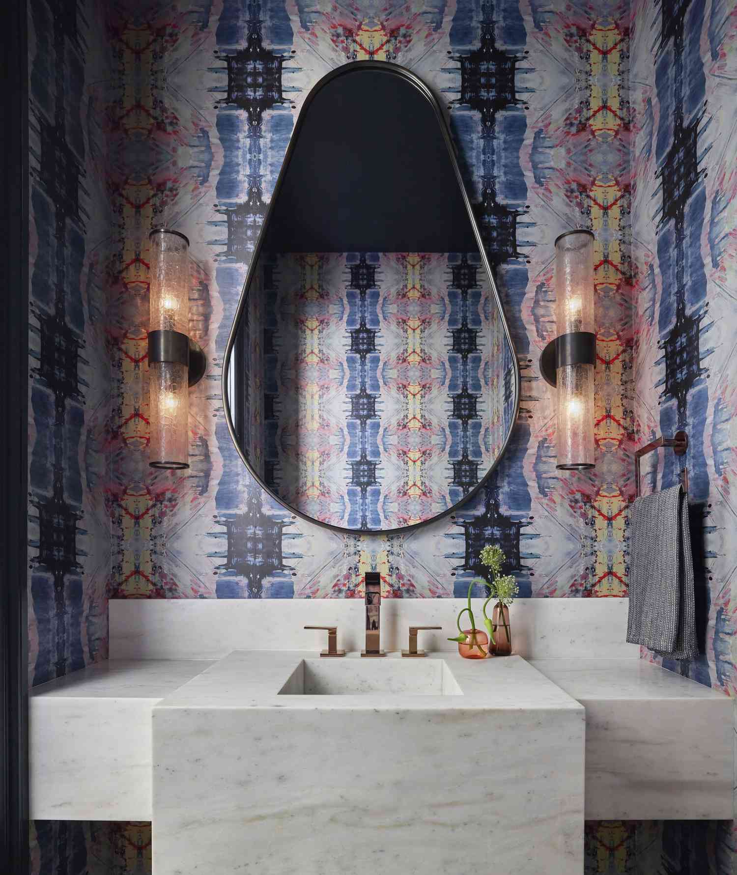 a teardrop mirror with patterned wallpaper 