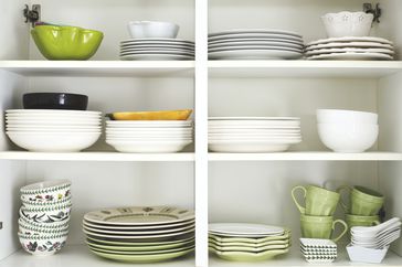 Tableware placed on a wooden shelf. Closeup of plates and dinnerware in a cupboard.