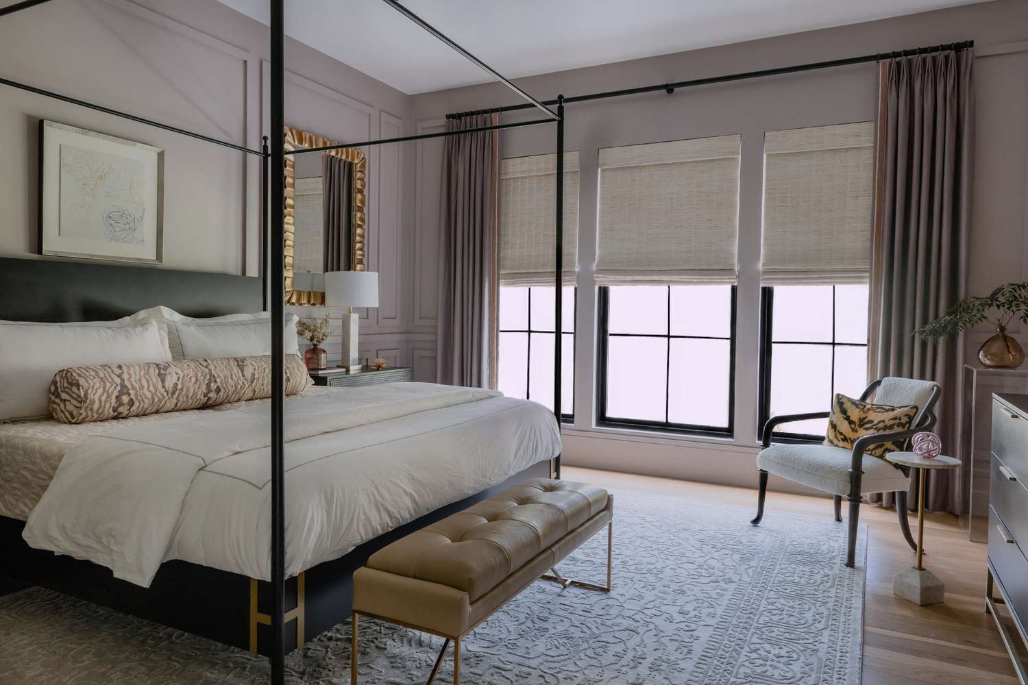 Modern bedroom with a canopy bed a bench and large windows with sheer coverings