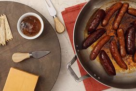 overhead view of a pan of sausages and a cheese plate