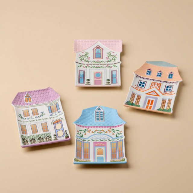 Four small decorative houses made of card or similar material featuring illustrated designs of windows doors and roofs