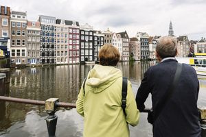 Two people standing by a river with urban wateredge buildings in the background