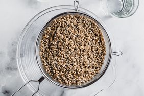 A sieve containing rinsed grains over a clear bowl