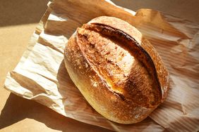 A loaf of sourdough bread on a crumpled paper bag