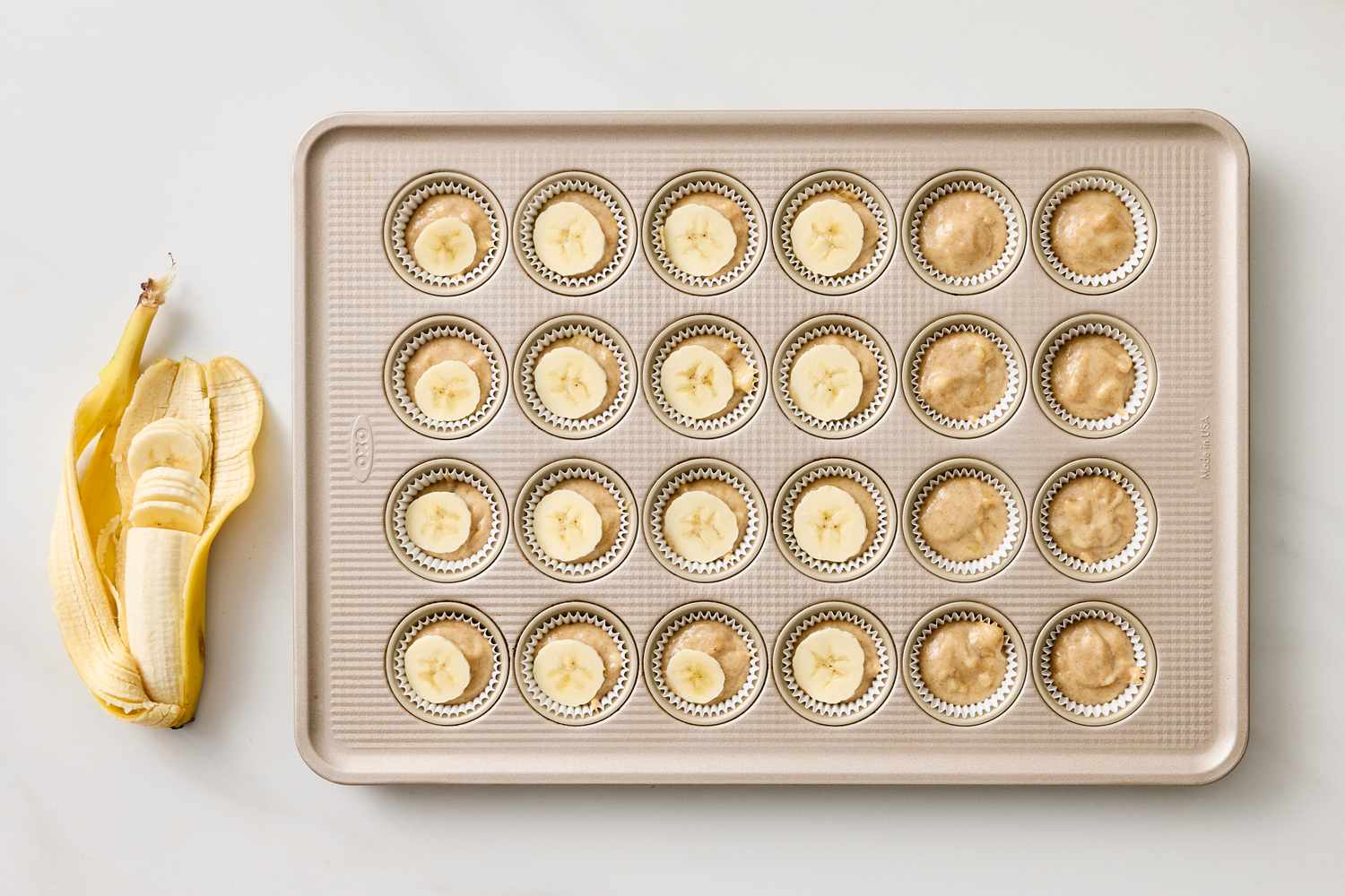 Mini banana muffins in a baking tray banana peel beside the tray