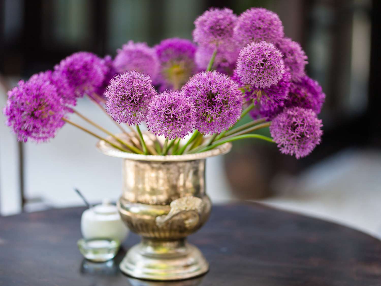 Purple spherical flowers in a silver vase on a table