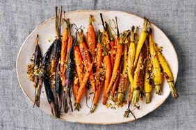 A platter of roasted carrots with seasoning and garnish