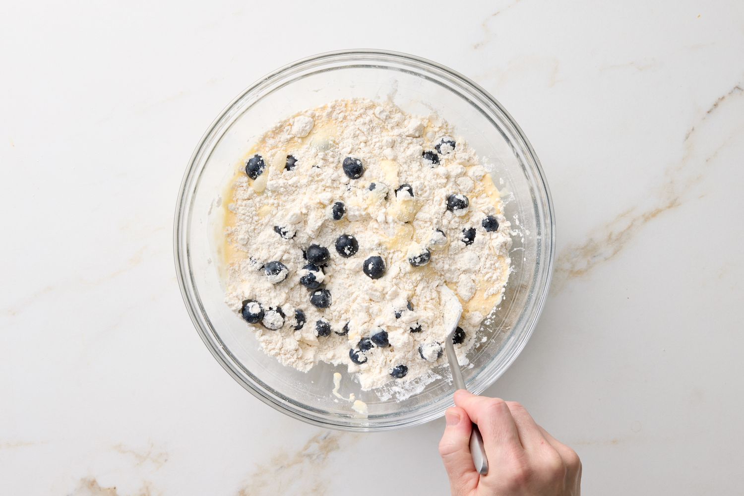 Mixing blueberry scone ingredients in a glass bowl