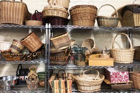A collection of woven baskets of various styles and sizes arranged on metal shelves