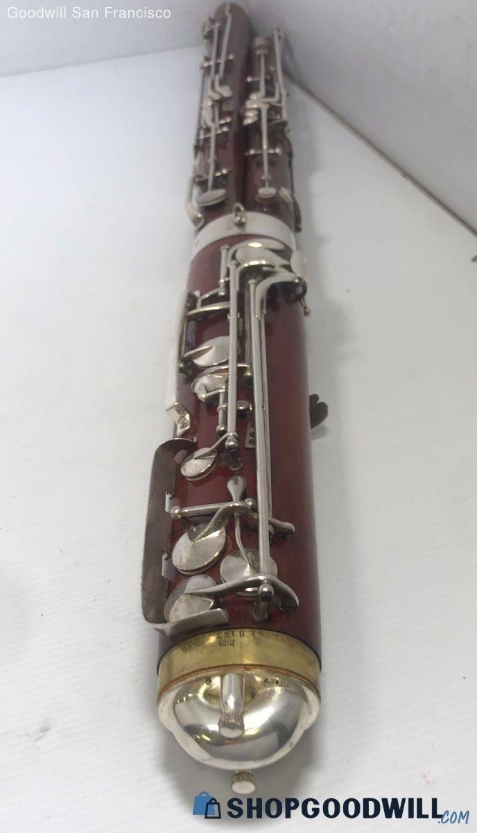 An antique bassoon displayed on a flat surface showing detailed keys and craftsmanship