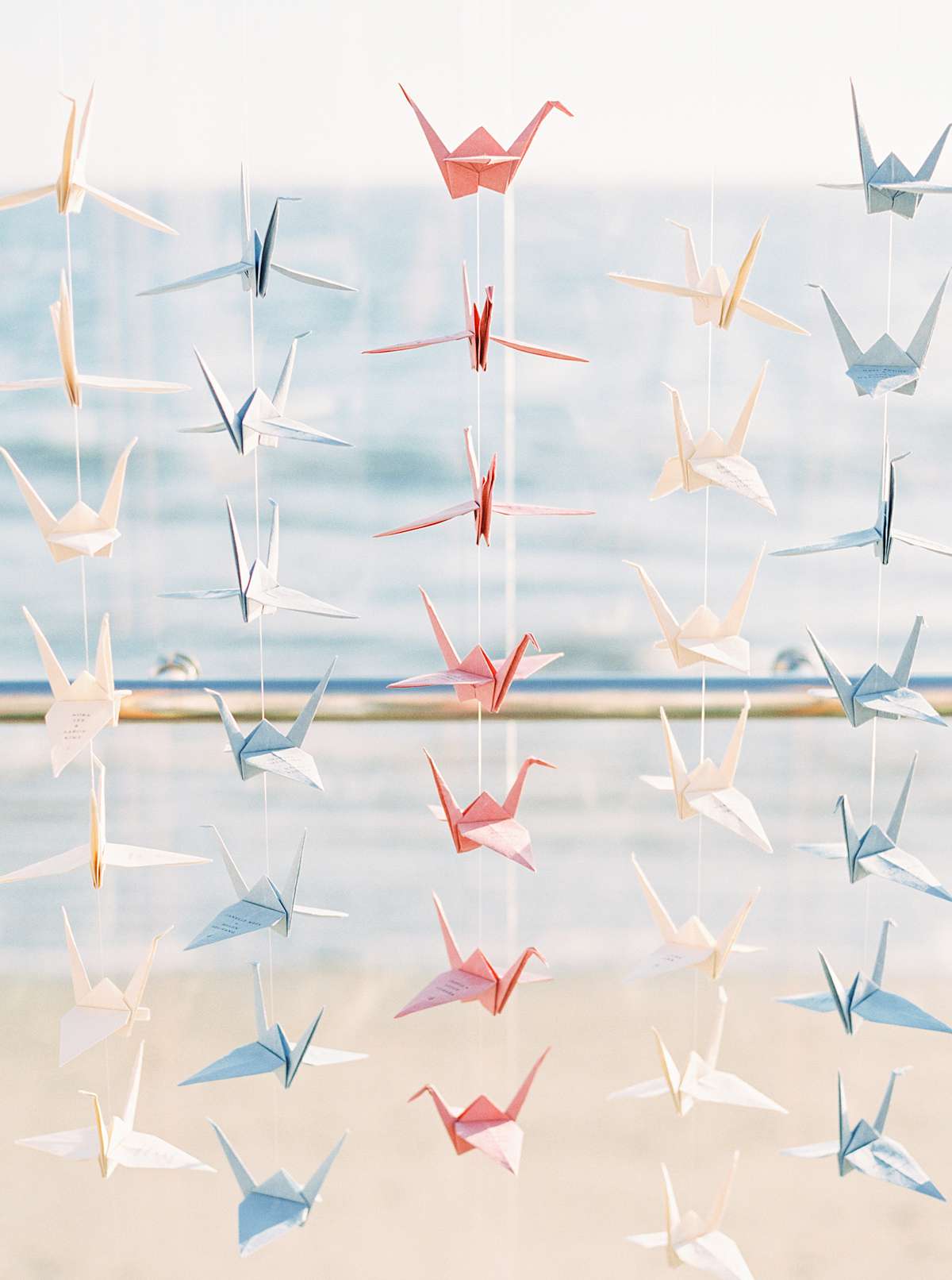 origami crane escort cards in tan, navy, and coral