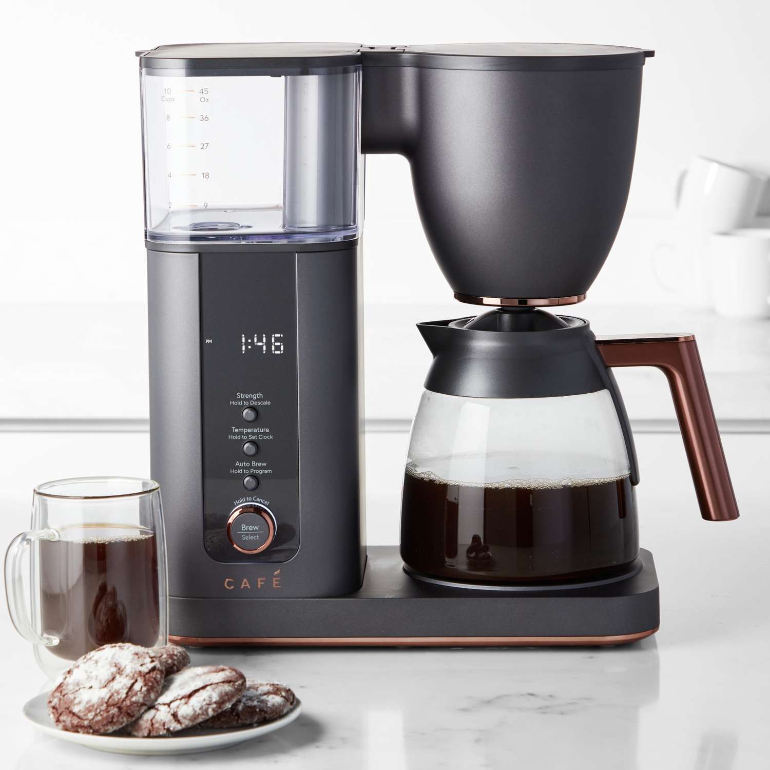 Drip coffee maker with carafe next to coffee and cookies