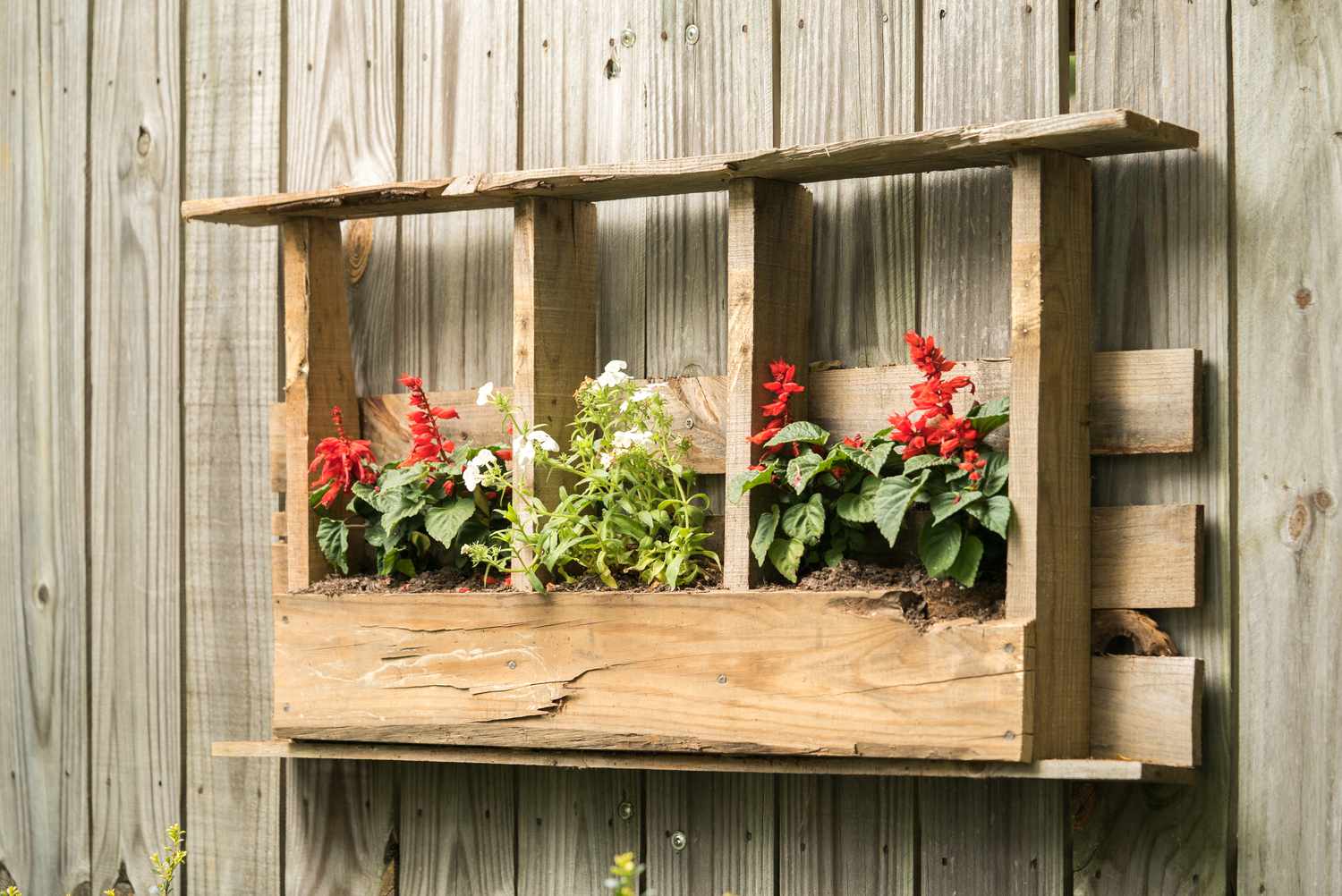 Handmade wooden flower basket hanging on wood fence in backyard