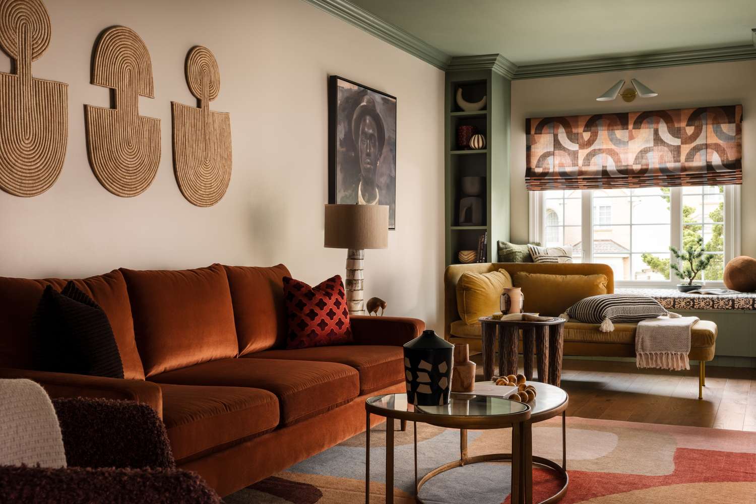 A living room with a sofa wall art a lamp and seating by a window