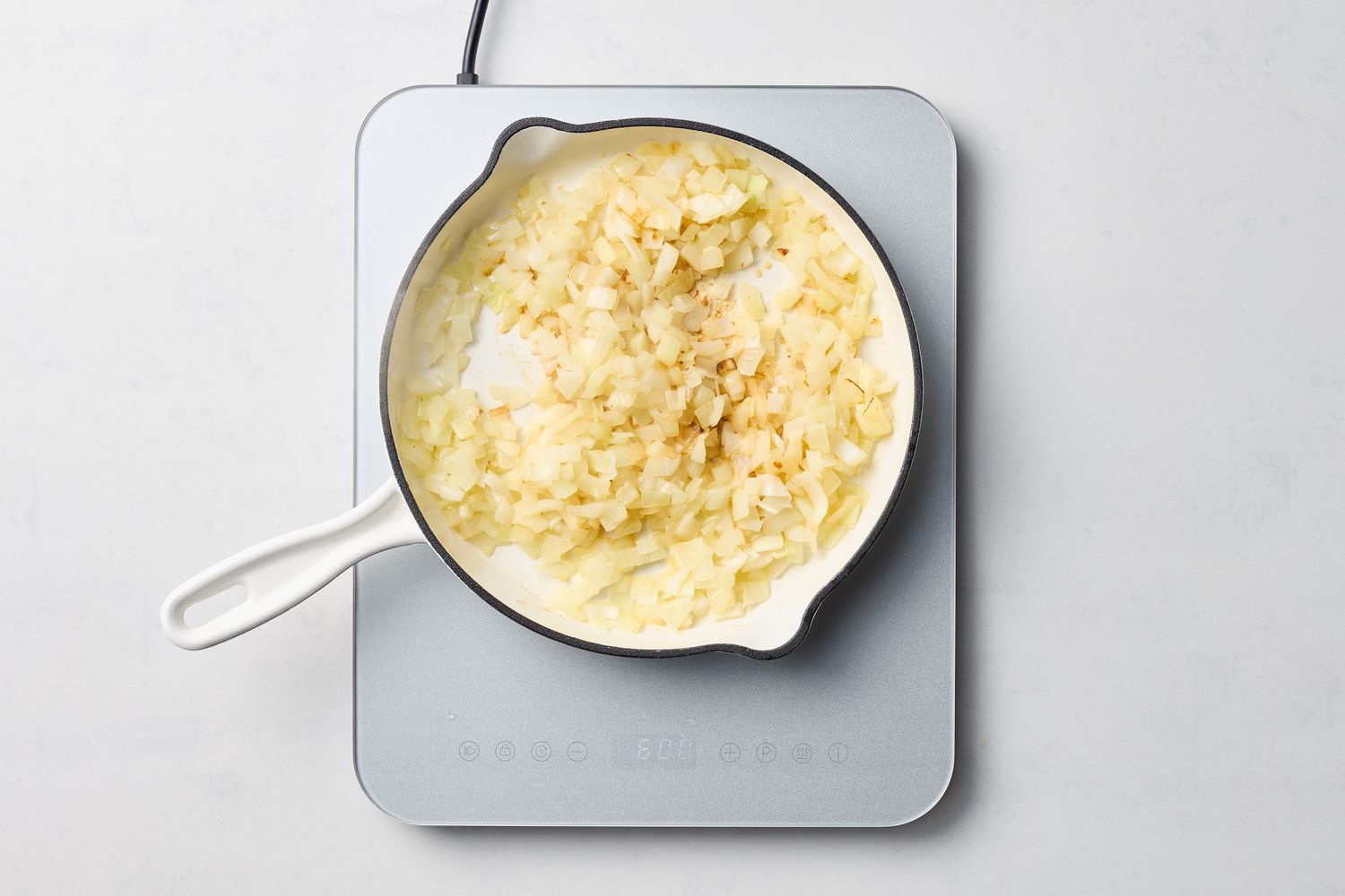 A saucepan filled with cooked onions on a heating element