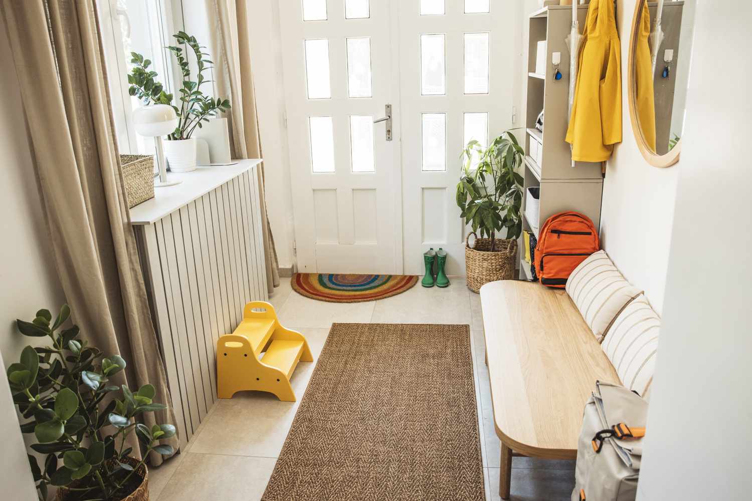 A home entryway with a bench potted plants and a coat rack