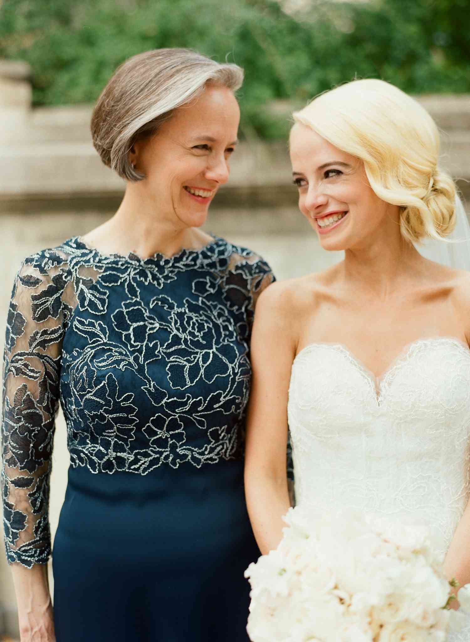 Smiling mother with bride standing outdoors