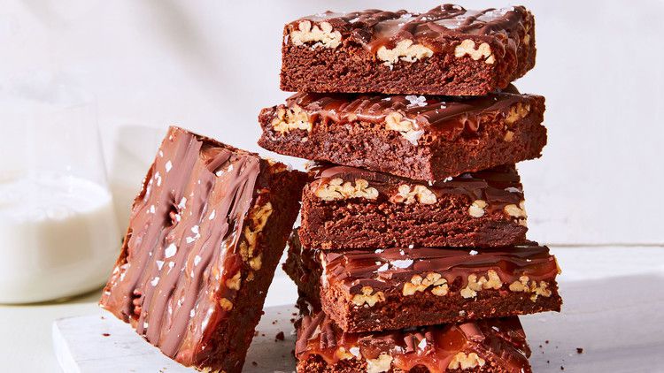 fudgy turtle brownies stacked on cutting board