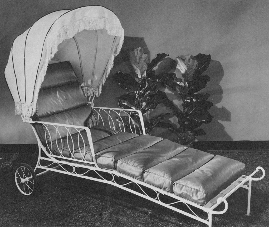 A vintage chaise lounge with a canopy located indoors near decorative plants