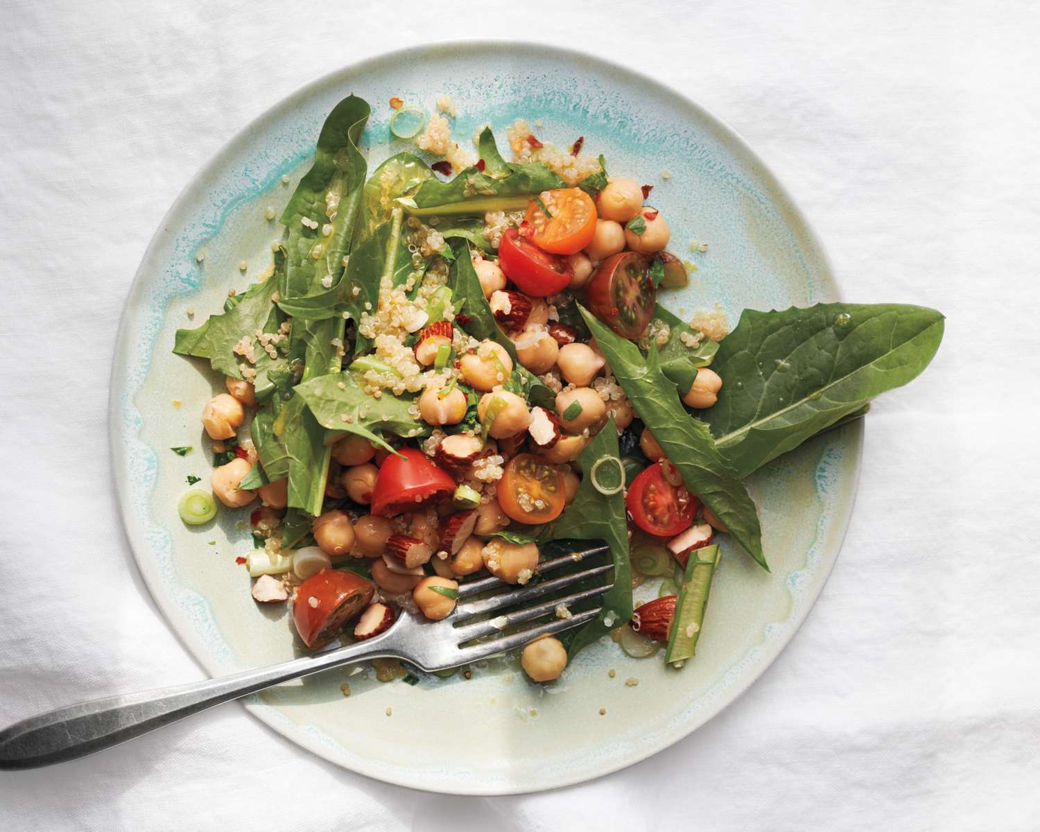 Salad with chickpeas greens and cherry tomatoes on a plate with a fork
