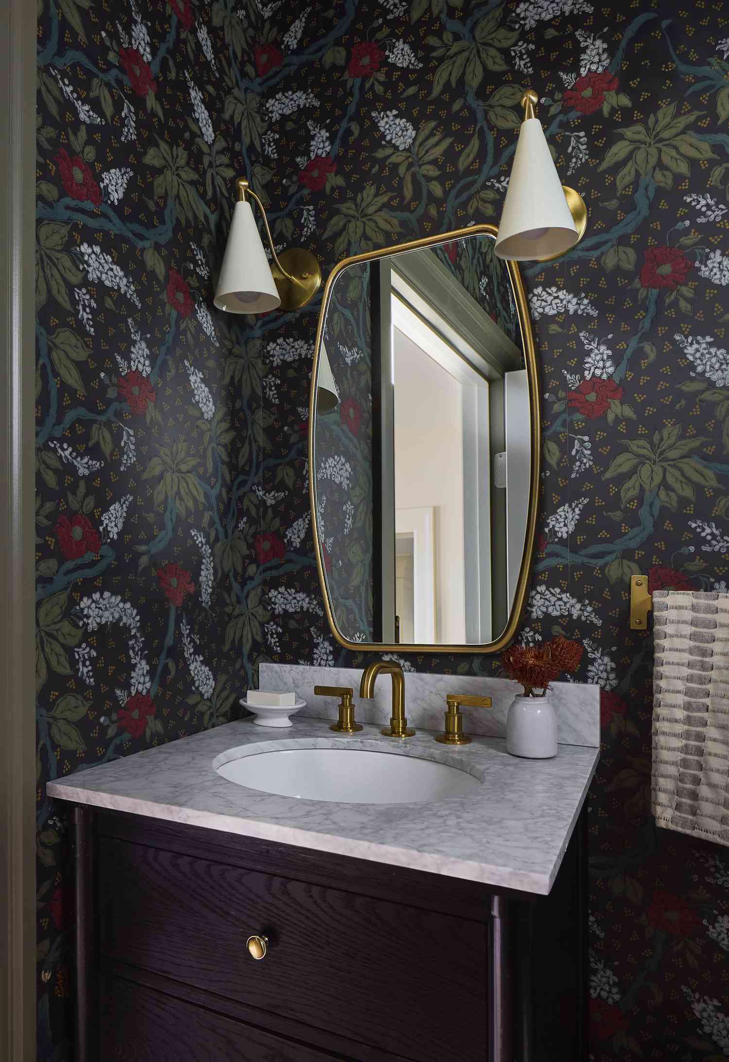a powder bathroom with botanical wallpaper and brass accents