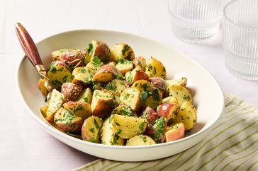 Bowl of a potato salad with herbs, placed on a striped napkin