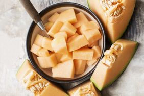 Bowl of cubed cantaloupe with sliced cantaloupe wedges and seeds surrounding