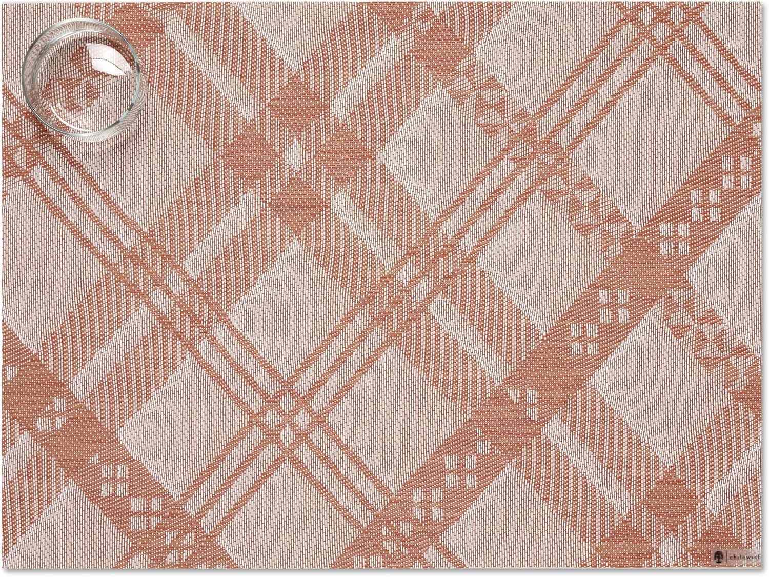 A textured placemat with a plaid pattern and a clear drinking glass on it
