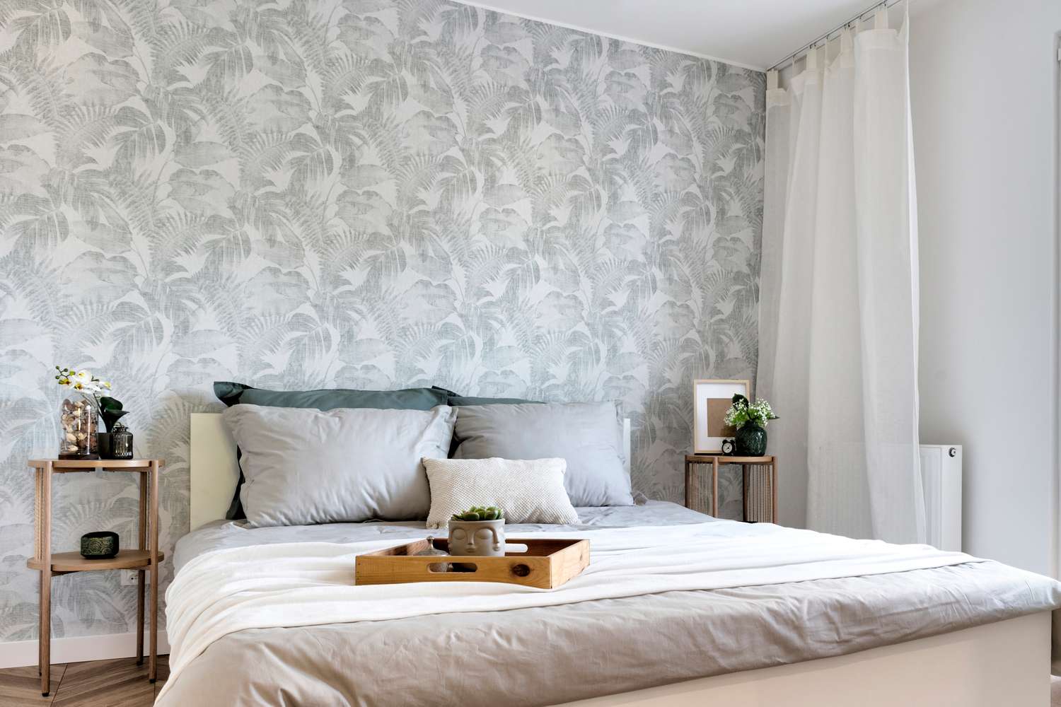 A bedroom with a bed bedside tables and a decorative accent wall with a patterned design