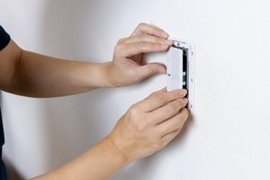 Hands installing or removing a wall-mounted device panel