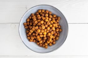 A bowl of roasted chickpeas on a white surface