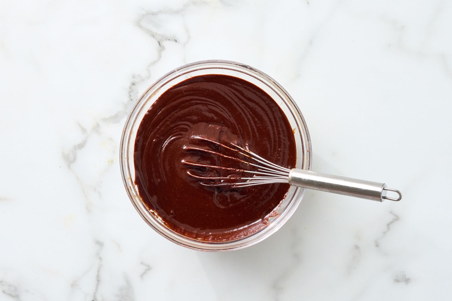 Bowl of brownie batter with a whisk on a countertop