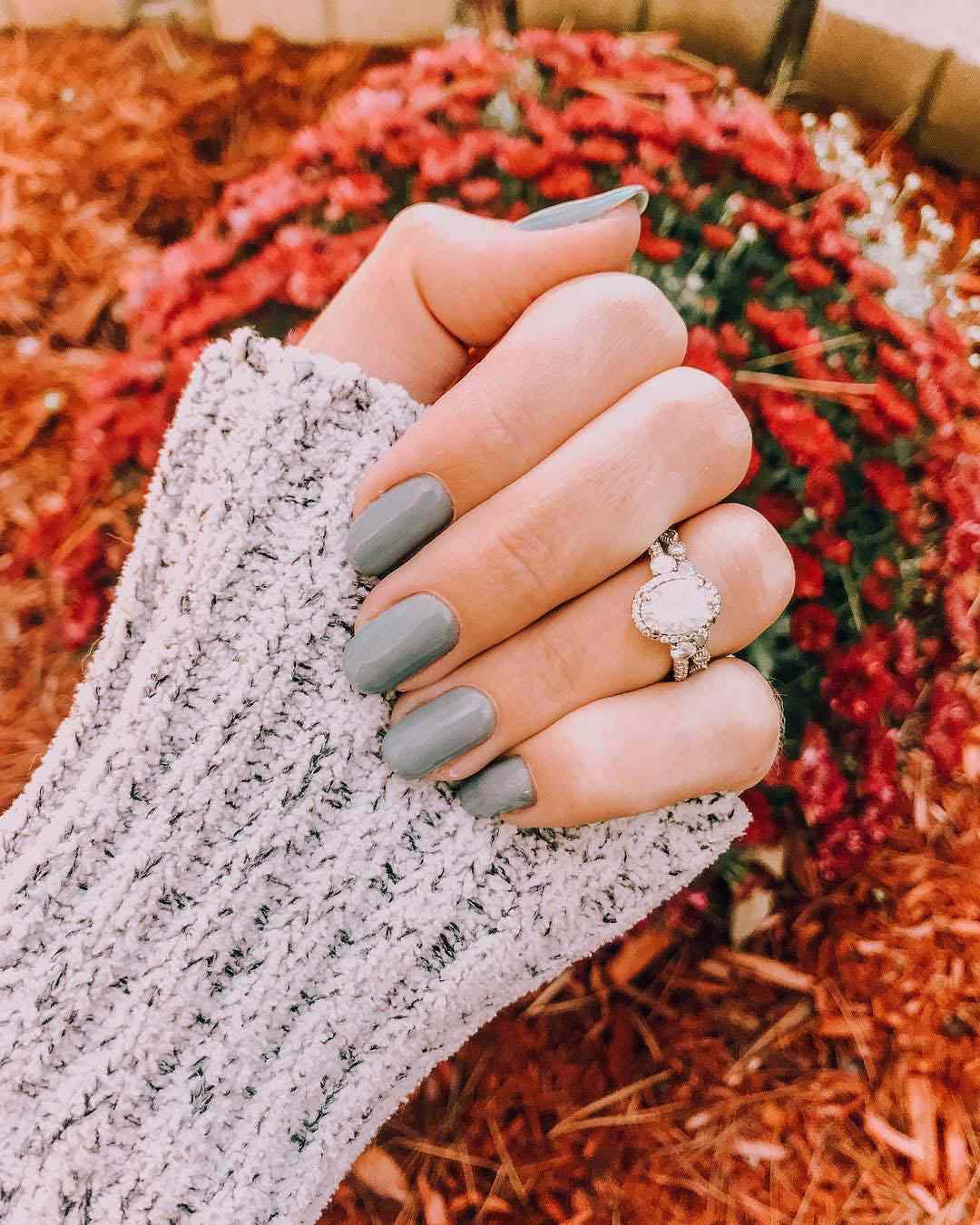 engagement ring selfie red floral backdrop and gray sweater
