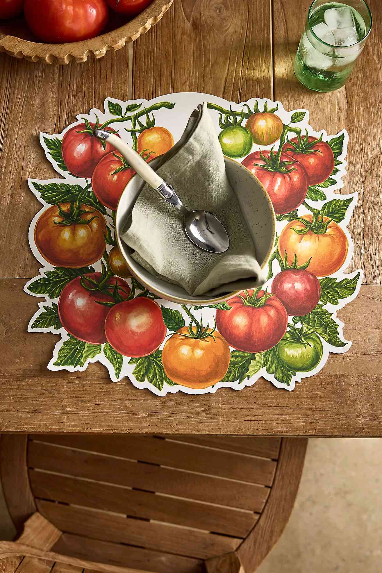 Dining table setting with tomato-themed placemat and napkin