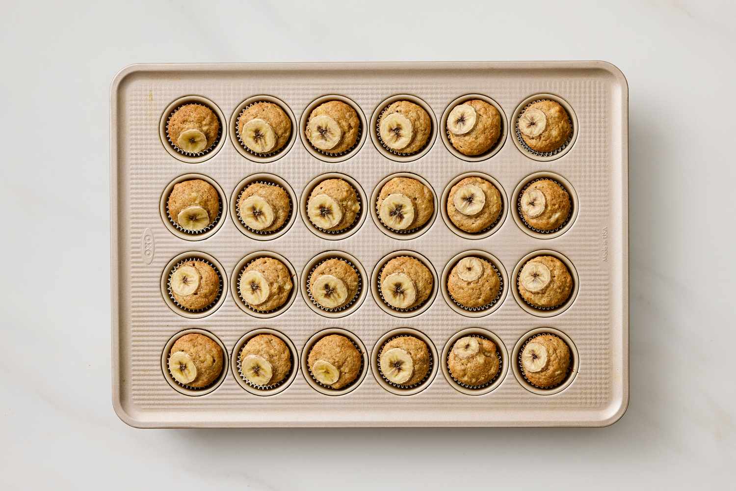 Tray of banana muffins topped with banana slices