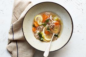 A bowl of quinoa vegetable soup with a spoon on a table