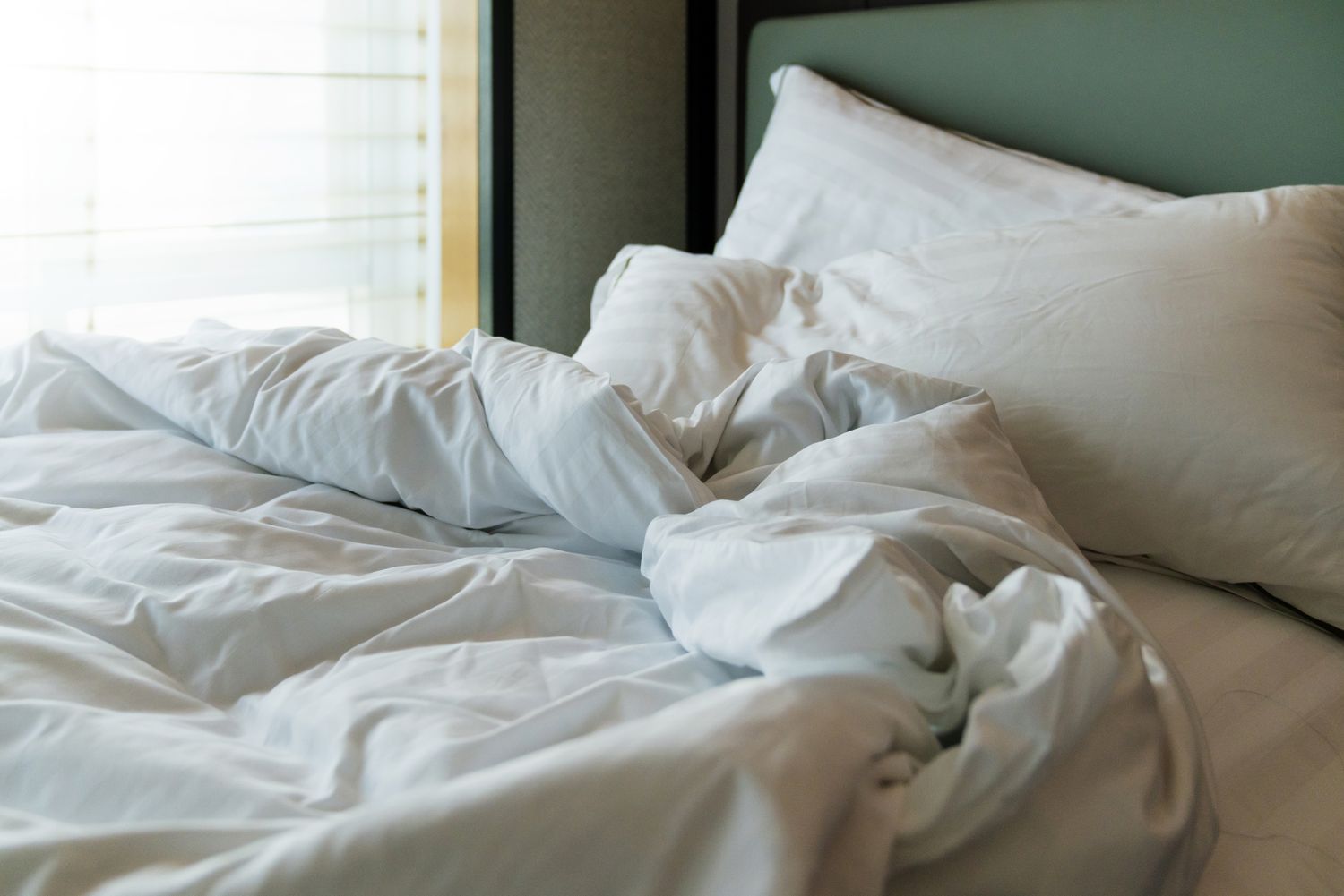 A messy unmade bed with crumpled sheets and pillows