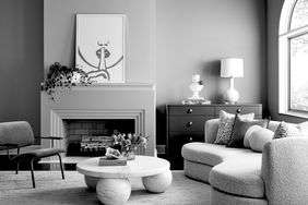 Modern living room interior with black-and-white decor, arched window, styled fireplace, furniture, and wall art
