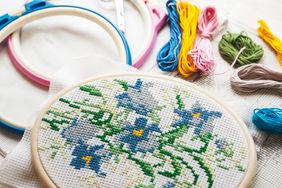 Embroidery in a hoop featuring a floral pattern with embroidery threads and tools nearby